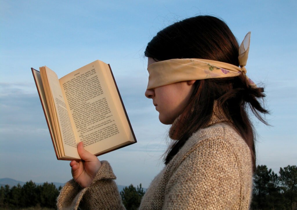 na mujer con una venda en los ojos leyendo un libro