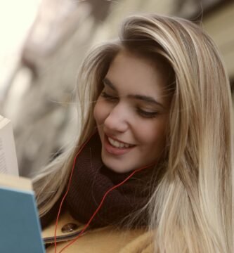 Imagen de una mujer en la calle leyendo un libro y sonriendo