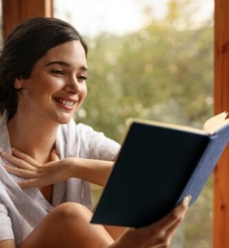 imagen de una mujer sonriente con cara de satisfacción mientras lee una novela corta