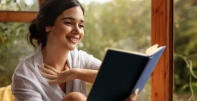 imagen de una mujer sonriente con cara de satisfacción mientras lee una novela corta