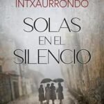 portada de la novela de Silvia Intxaurrondo Solas en el silencio, en la que debajo del título se ve a unas mujeres en un callejón cobijándose de la lluvia con un paraguas.
