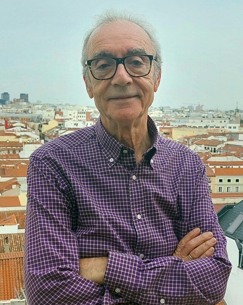 imagen frontal de juan josé millás en la que parece sonriente con los brazos cruzados