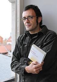 imagen de isaac rosa en la que aparece de perfil con un libro en la mano