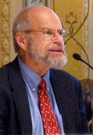 imagen de lawrence block en la que aparece en traje y corbata y tiene delante de el un micrófono.