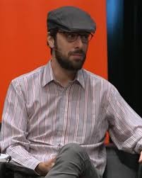 imagen de david uclés en la que aparece sentado con una camisa y una boina