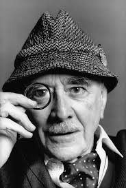 foto frontal de Manuel Mujica Lainez, en la que aparece con un gorro y sosteniendo un monóculo cerca de uno de sus ojos.